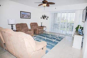 sala de estar con sofá, sillas y ventilador de techo en Oceanwalk 12-404, en New Smyrna Beach