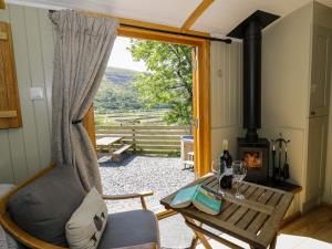 a living room with a table and a wood stove at Moelfre - Shepherds Hut in Llanbedr