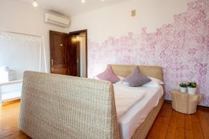 1 dormitorio con 1 cama con silla de mimbre en Casa Ortensia: rustico ristrutturato in pietra, en Rive dʼArcano