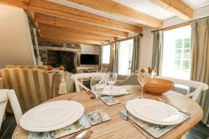a wooden table with plates and wine glasses on it at 2 Rose Cottages in St. Agnes 