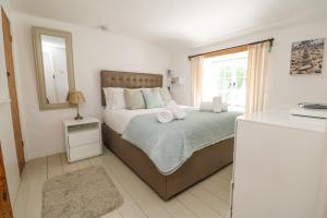 a bedroom with a bed with a mirror and a window at 2 Rose Cottages in St. Agnes 