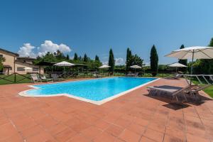 einen Pool mit 2 Stühlen und einem Sonnenschirm in der Unterkunft Appartamento Colombaia in Laterina