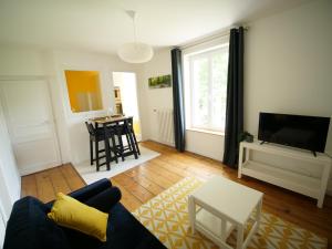 a living room with a blue couch and a tv at Les Gîtes du Couesnon in Pontorson