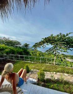 a woman sitting on the steps of a house at Ocean Glamping Penida in Nusa Penida