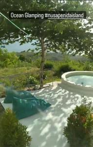 a garden with a swimming pool and a tree at Ocean Glamping Penida in Nusa Penida