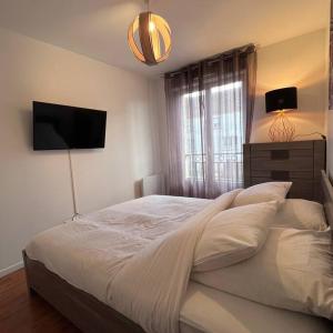 een slaapkamer met een groot bed en een televisie aan de muur bij Appartement Cosy proche Disney in Pontault-Combault