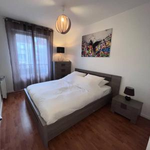 una camera con un grande letto bianco e una lampada di Appartement Cosy proche Disney a Pontault-Combault