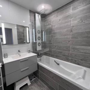 een badkamer met een bad, een wastafel en een bad bij Appartement Cosy proche Disney in Pontault-Combault