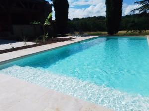 una piscina de agua azul en un patio en Gite LOT'ivier Piscine et Lot 2 à 4 pers, en Montayral