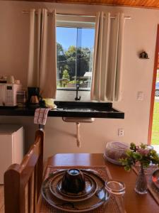 uma cozinha com uma mesa, uma pia e uma janela em Chalés Vale do Sossego em Monte Verde