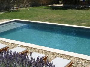 una piscina en un patio con sillas y flores púrpuras en Mas de village avec piscine et grand jardin clôturé, en Fournès