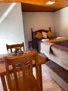 uma sala de estar com uma cama, uma mesa e cadeiras em Chalés Vale do Sossego em Monte Verde