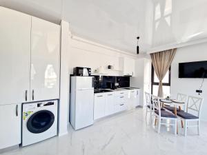 a white kitchen with a washing machine and a table at Studio Armsea Mamaia Nord in Mamaia