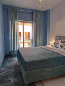 a bedroom with a bed with blue walls and a window at Gala Premium in Nea Potidaea