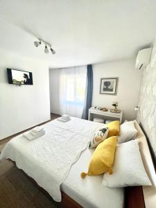 a bedroom with a large white bed with yellow pillows at Sun&Fun Studio Apartment in Hvar