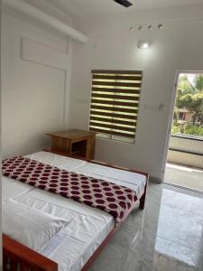 a bedroom with a bed and a table and a window at New star homes in Kotamangalam