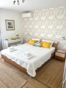 1 dormitorio con 1 cama blanca grande con almohadas amarillas en Sun&Fun Studio Apartment en Hvar