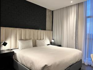 a bedroom with a large white bed with a black wall at The Urban Hotel Lusaka in Lusaka