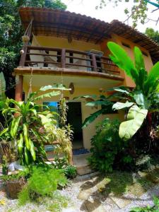 a small yellow house with a balcony in a garden at Residencial Caetanos - 5 casas em Arraial D'ajuda in Porto Seguro