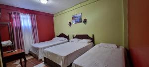 Duas camas num quarto com paredes vermelhas e verdes em Hotel Los Andes Tegucigalpa em Tegucigalpa
