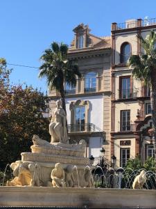una fuente frente a un edificio con una estatua en Hotel Tayko Sevilla, en Sevilla