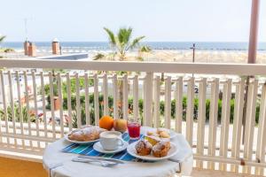 a table with two plates of food on a balcony with the beach at Hotel Carnaby in Rimini