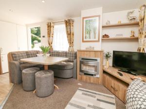 a living room with a couch and a tv and a table at Horizon in Combe Martin