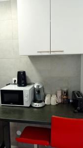 a kitchen counter with a microwave and a red chair at Superbe appartement Disneyland Paris Parking in Lagny