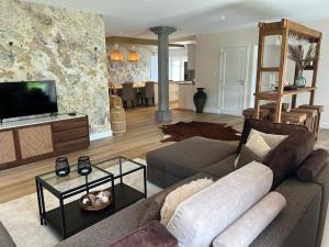 a living room with a couch and a tv at Jacuzzi - Sauna - BBq - Jardin - Garden Lodge - Myosotis in Olne