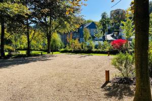 a park with trees and a house in the background at Jacuzzi - Sauna - BBq - Jardin - Garden Lodge - Myosotis in Olne +32 photos