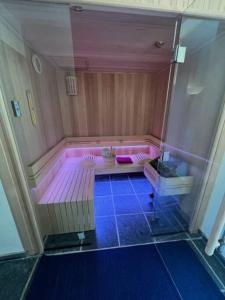 a pink bath tub with a purple floor in a room at Jacuzzi - Sauna - BBq - Jardin - Garden Lodge - Myosotis in Olne