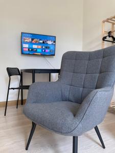uma cadeira cinzenta sentada ao lado de uma mesa com uma televisão em Apartment am Kino em Bautzen
