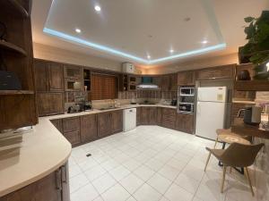 a large kitchen with wooden cabinets and white appliances at العلا بيتك in AlUla