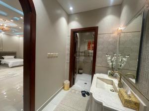 a bathroom with a sink and a shower with a mirror at العلا بيتك in AlUla