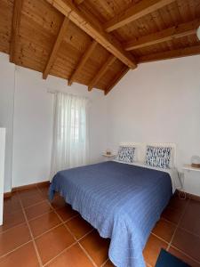 a bedroom with a blue bed with a wooden ceiling at Sudoeste Guest House in Odeceixe