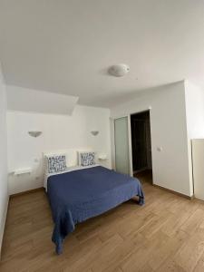 a bedroom with a blue bed in a white room at Sudoeste Guest House in Odeceixe