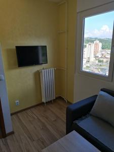 a living room with a tv and a couch and a window at stan na dan IM in Užice