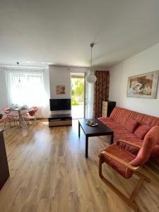 a living room with a red couch and a table at Apartament z garażem i ogrodem in Kołobrzeg