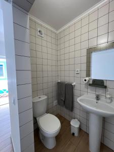 a white bathroom with a toilet and a sink at Sudoeste Guest House in Odeceixe