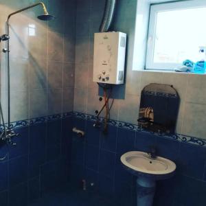 un bagno piastrellato blu con lavandino e finestra di Samist Villa a Gabala