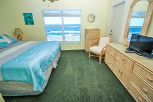 a bedroom with a bed and a desk with a television at Sea Coast Gardens III 303 in New Smyrna Beach