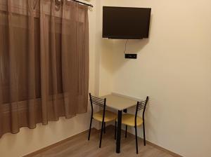 een tafel met twee stoelen en een televisie aan de muur bij Apartment Dipla 3 in Athene