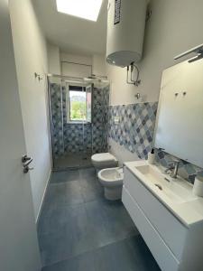 La salle de bains est pourvue de 2 lavabos, de toilettes et d'un miroir. dans l'établissement Marè Diamante, à Diamante