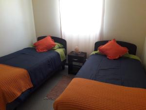 2 łóżka z pomarańczowymi poduszkami w pokoju w obiekcie Pura Vida El Molle w mieście Vicuña