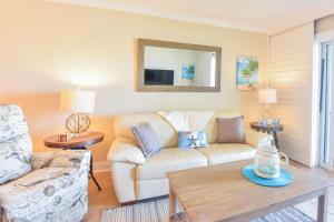 uma sala de estar com um sofá e uma mesa em Sea Coast Gardens II 105 em New Smyrna Beach