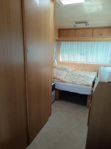 um pequeno quarto com uma cama e uma janela em Camping Mauritius em Mielno