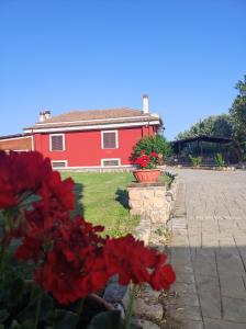 a red house with red flowers in front of it at B&B Sole e Luna in Scurcola Marsicana