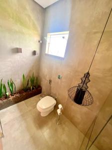 a bathroom with a toilet and a plant at Lara's Home Suites in Capitólio