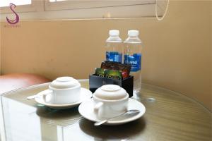 a glass table with two tea cups and bottles of water at Suji My Dinh Hotel in Hanoi