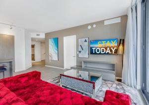 HYDE BEACH HOUSE #2408 THREE-BEDROOM, WATERFRONT, OCEAN AND INTERCOSTAL VIEW, ROOFTOP POOL, 5 MiN WALK TO BEACH في هوليوود: غرفة معيشة مع سرير احمر وتلفزيون